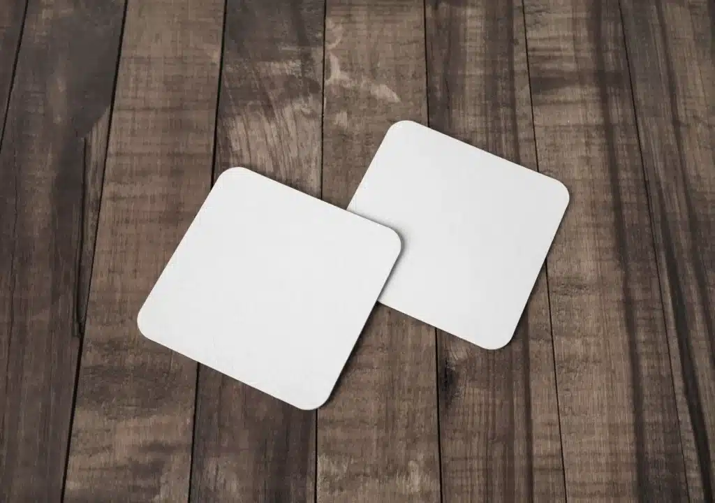two white square custom coasters on a table by DigitalPrinting.Ph