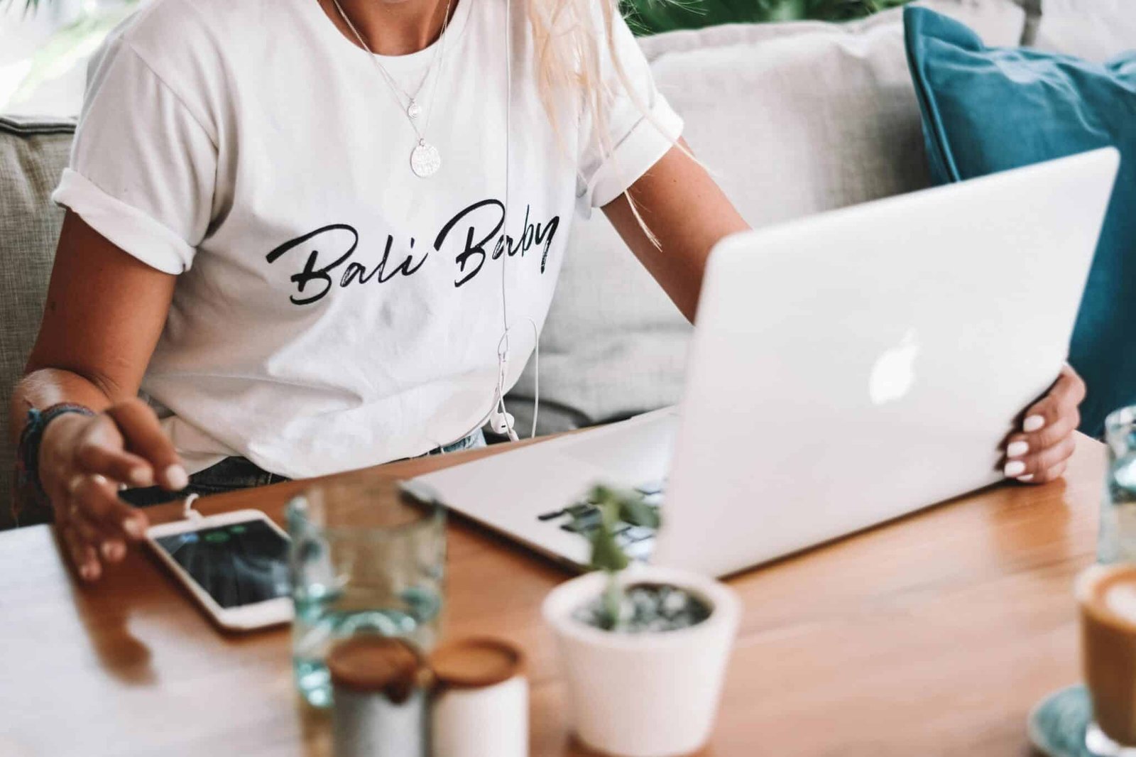 Girl wearing white shirt with black print on chest, sitting with a laptop in a cafe – tshirt printing